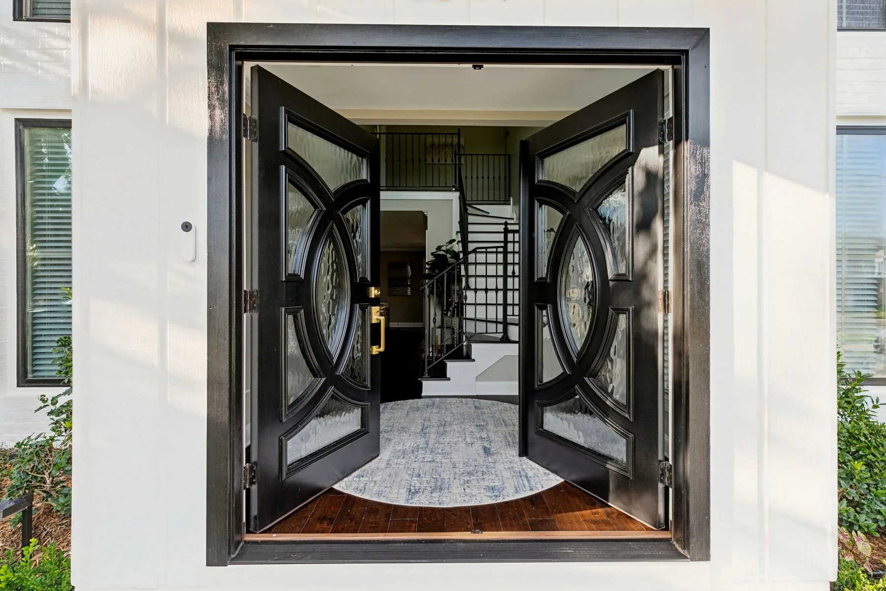 Black double doors open onto a bright foyer