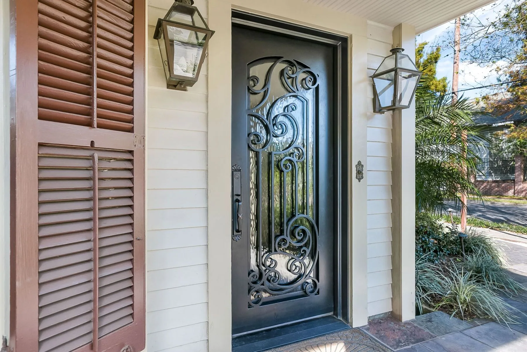 Black wrought iron scrollwork door between gas lanterns